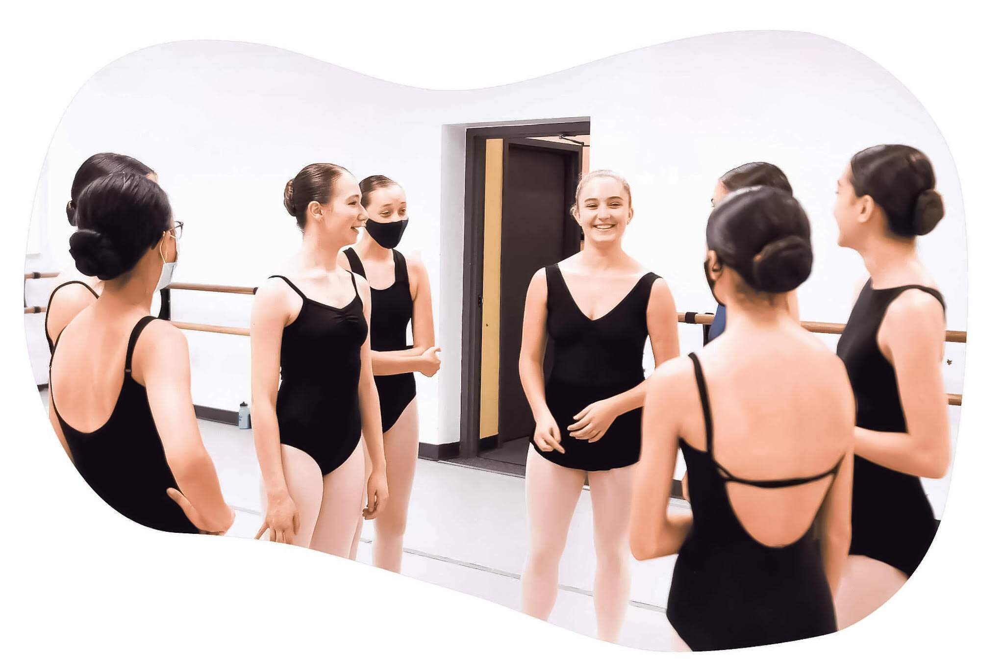 A group of ballerinas talking to each other in a ballet studio